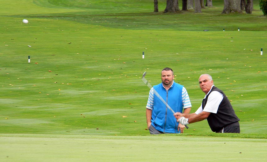 Jim Cea pitches to the final green while John Kabasky watches them seal up a big win.