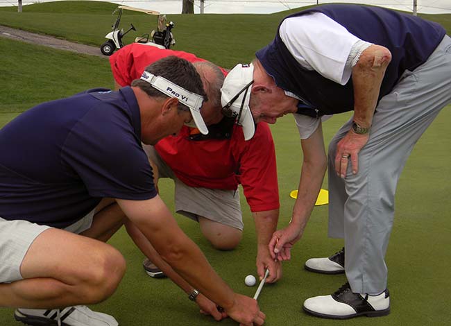 Ty Kovach (l) helps Tim Davis and Dave Chapple determine the winner of the Dave Towell Cadillac Shootout